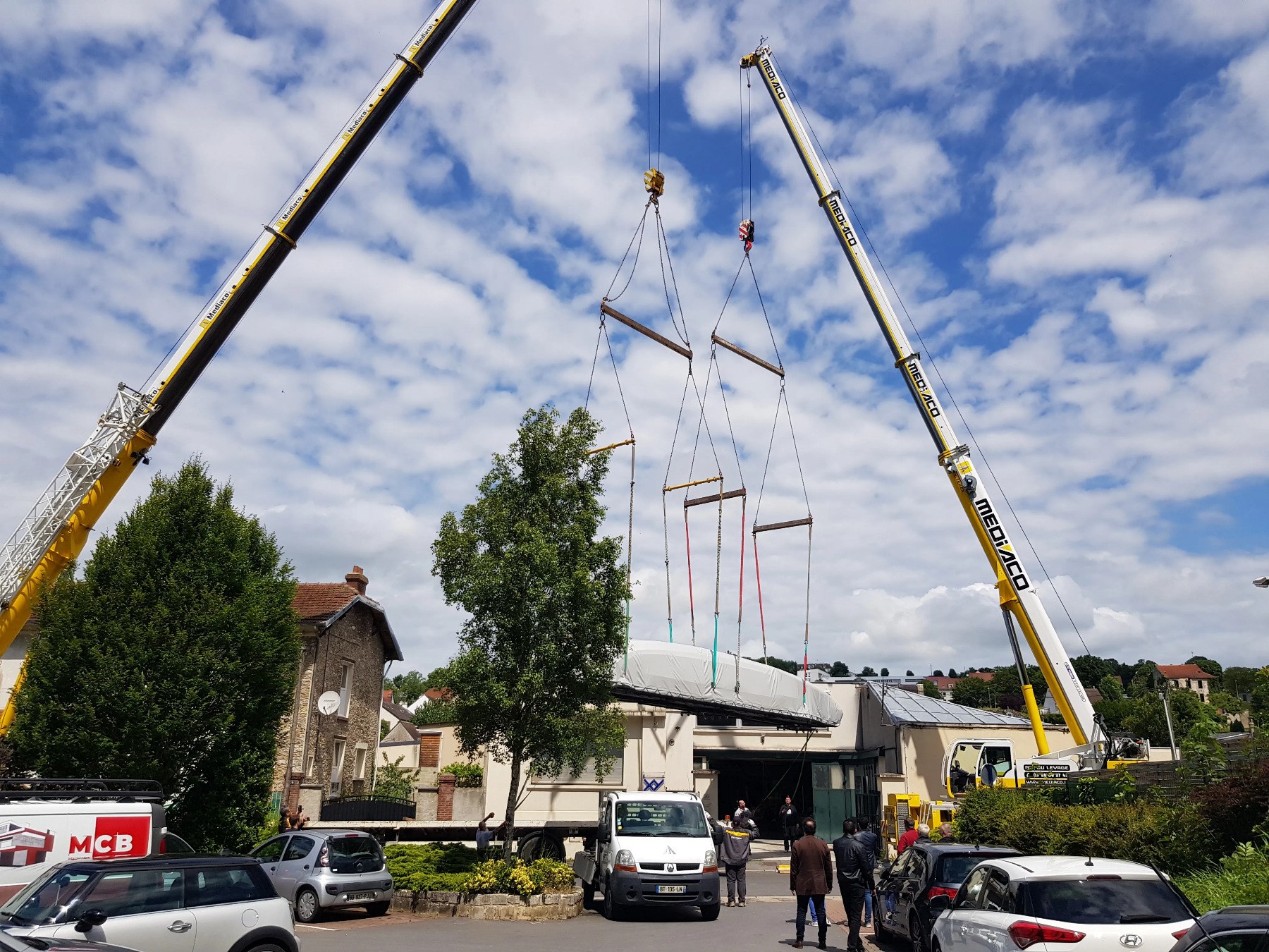 Sub-photo — Deux grues pour la sortir de l'atelier : sa longueur imposait un levage en quatre points, au-dessus des toits.